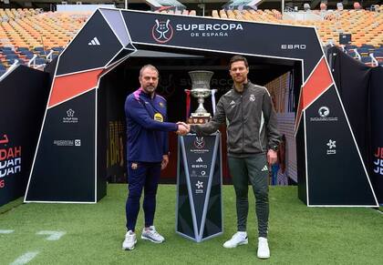 Hansi Flick y Xabi Alonso se dan la mano junto al trofeo en la previa de la Supercopa de España