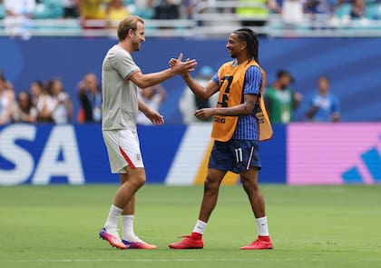 Harry Kane se saluda con Michael Olise, compañeros en Bayern Munich