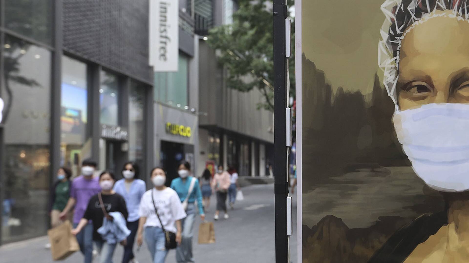 Hasta la Mona Lisa en un afiche publicitario de una peluquería usa barbijo en las calles de Seúl, Corea del Sur
