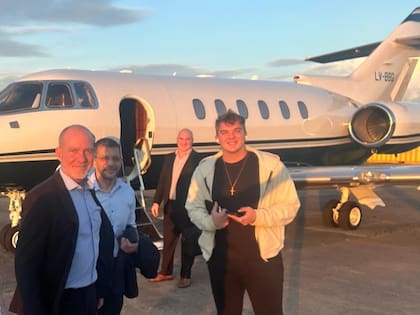 Hayden Davis, de campera color crema, antes de subir a un jet durante su visita a la Argentina