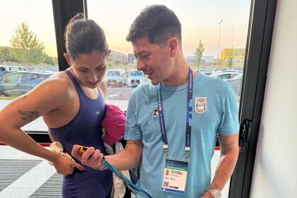 Hein y su entrenador, Sebastián Montero, mirando la medalla plateada conseguida en el Mundial junior de natación en Rumania