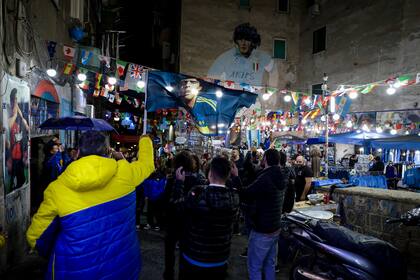 Hinchas cantan frente a un mural gigante de Diego Maradona en el aniversario de su muerte, en el Barrio Español de Nápoles, Italia, el lunes 25 de noviembre de 2024. (Alessandro Garofalo/LaPresse vía AP)