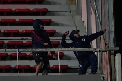 Hinchas de Universidad de Chile lanzan piedras durante un partido de la Copa Sudamericana en cancha de Independiente de Argtnina, el miércoles 20 de agosto de 2025 (AP Foto/Gustavo Garello)