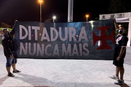 Hinchas del club Vasco da Gama con una bandera contra Bolsonaro, en las cercanías del estadio Maracaná
