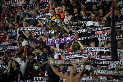 Hinchas del Paris Saint-Germain sostienen sus bufandas durante el partido de la liga francesa contra el Montpellier, en el estadio del Parque de los Príncipes, en París, el sábado 25 de septiembre de 2021. (AP Foto/Christophe Ena)