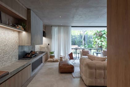 Hogar de hormigón flanquedado por revestimiento de pared (Travertinos & Piedras) y muebles amurados (Woodhead). Piso de porcelanato (Barugel).