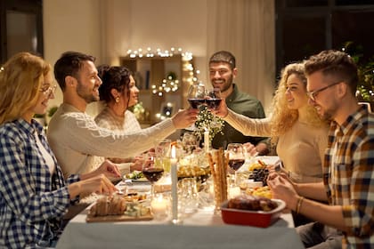holidays, celebration and people concept - happy friends having christmas dinner party and drinking non-alcoholic red wine at home