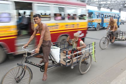 Hombre en bici llevando un monje en el Puente Howrah en Calcuta.