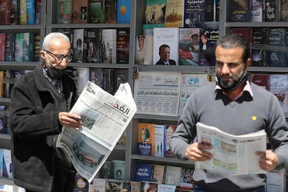 Hombres jordanos leen periódicos locales con titulares sobre los últimos eventos en su país, frente a un quiosco en la capital, Ammán, el 4 de abril de 2021