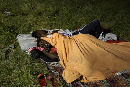Hombres que fueron desplazados de sus viviendas, luego de que éstas quedaron reducidas a escombros por un sismo de magnitud 7,2, duermen en el exterior de un hospital en Les Cayes, Haití, el sábado 14 de agosto de 2021. (AP Foto/Joseph Odelyn)