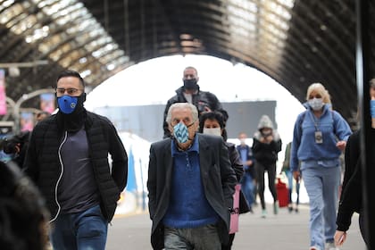 Hombres y mujeres con barbijo observan el distanciamiento tras descender del tren, en la estación Retiro