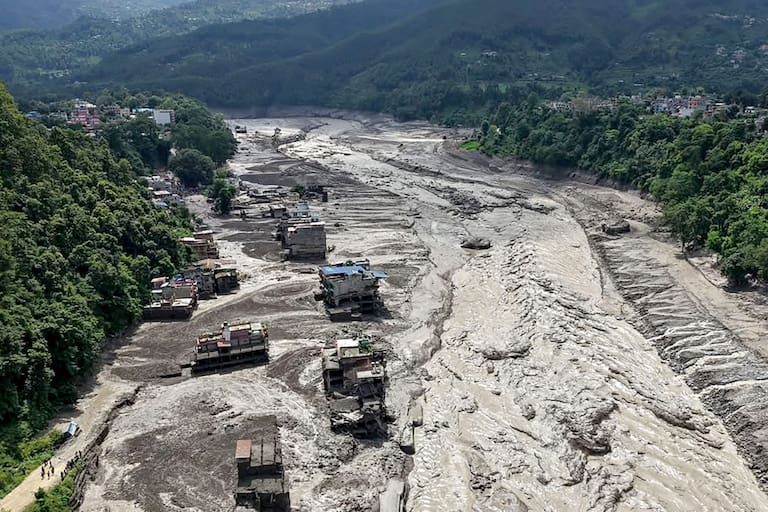 Houses lie partially submerged in muddy water along a riverside after flash floods at Trishuli Bazar in Nepal's Nuwakot district on August 26, 2026. A massive flood swept through Nepal's northern Rasuwa district on August 26, damaging roads and power infrastructure as authorities scrambled to assess the scale of the destruction. (Photo by Prabin RANABHAT / AFP)
