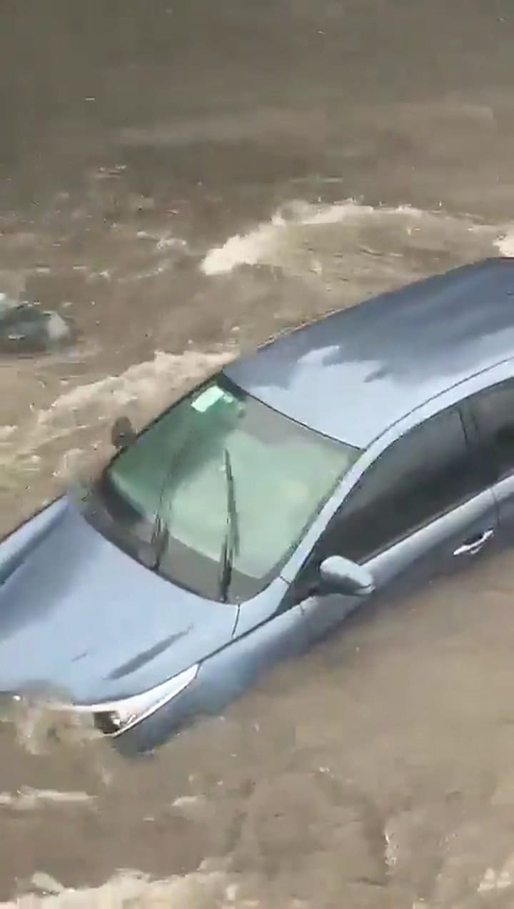 Un hombre intenta manejar su auto mientras el agua lo arrastra