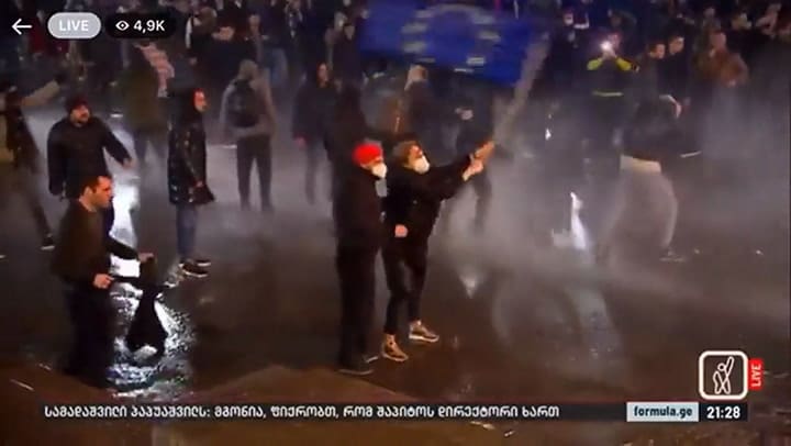 Mujer sosteniendo una bandera de la UE sola frente a un cañón de agua