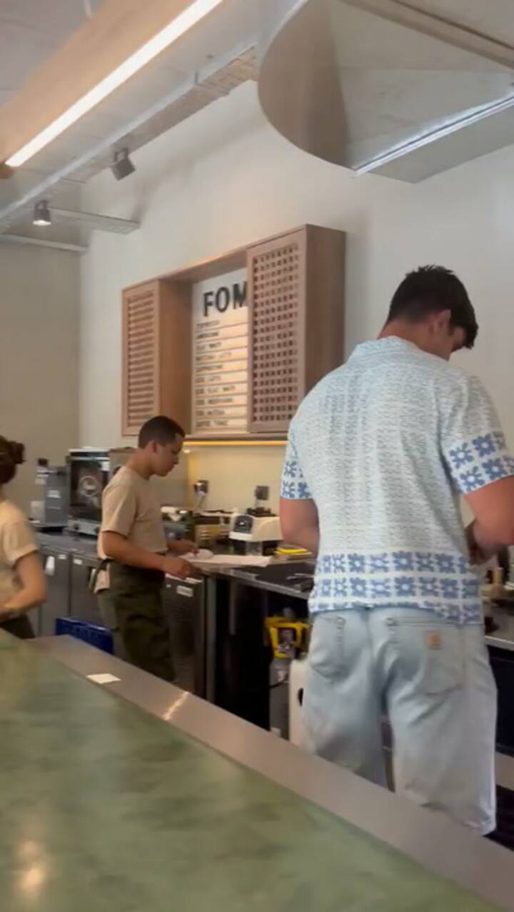 Tomás Lavanini con su camisa neocelandesa atendiendo su café