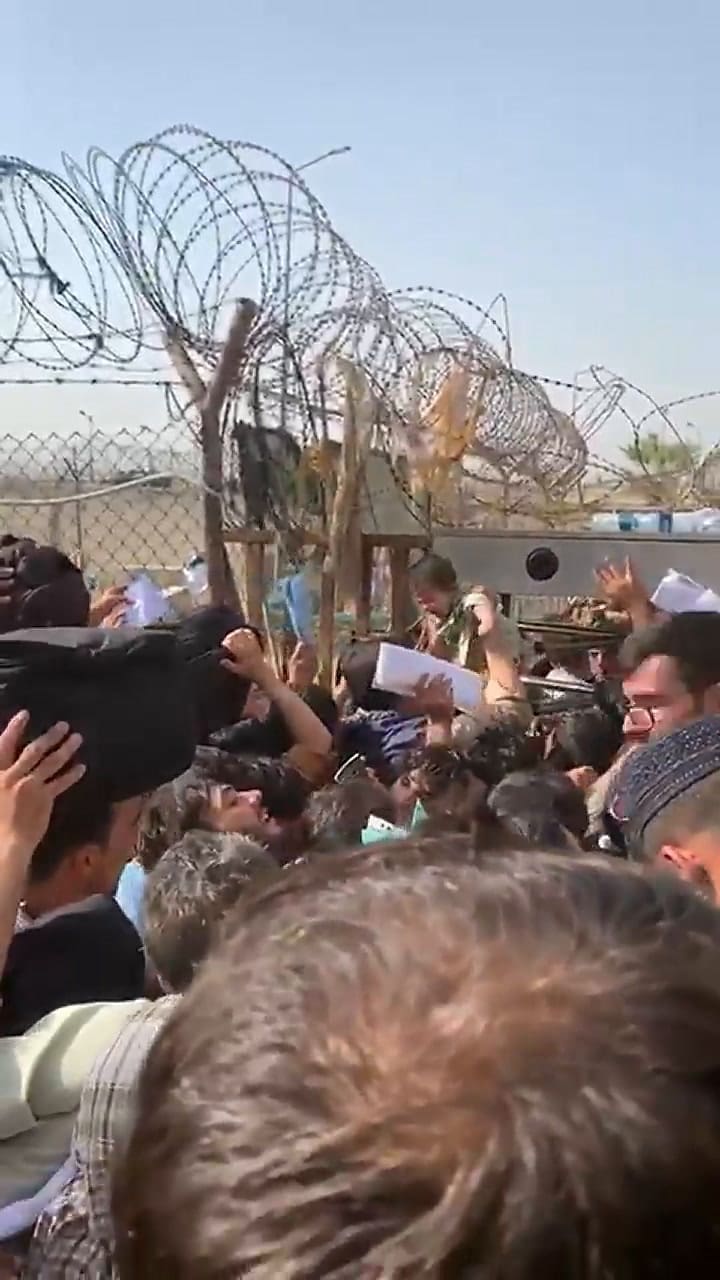 Una niña afgana es levantada entre la multitud para ser rescatada por soldados estadounidenses