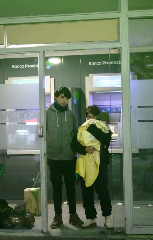 Hugo, Sofía y Lucas, de un año, en la puerta del cajero donde solían pasar la noche.