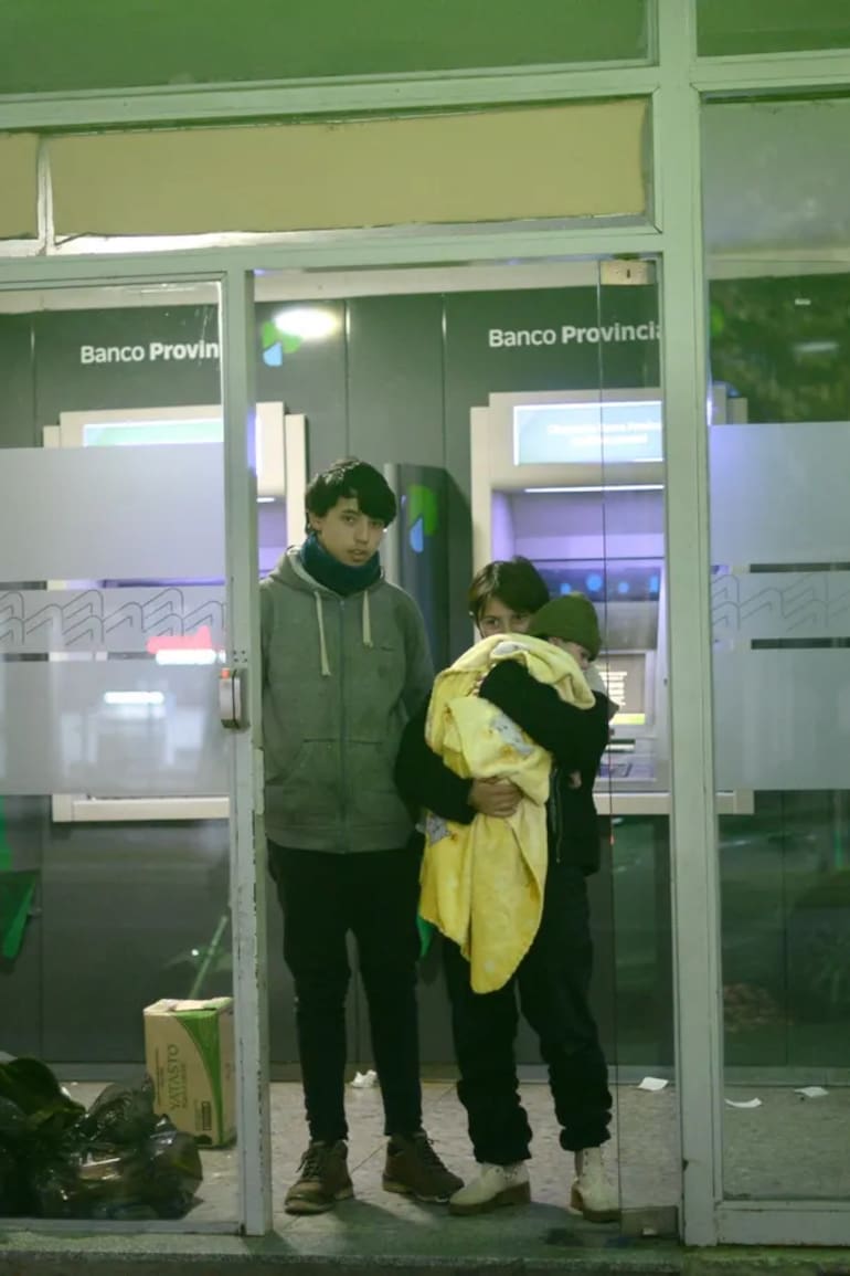 Hugo, Sofía y Lucas, de un año, en la puerta del cajero donde solían pasar la noche.