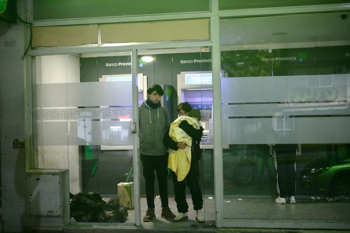Hugo, Sofía y Lucas, de un año, en la puerta del cajero donde solían pasar la noche.