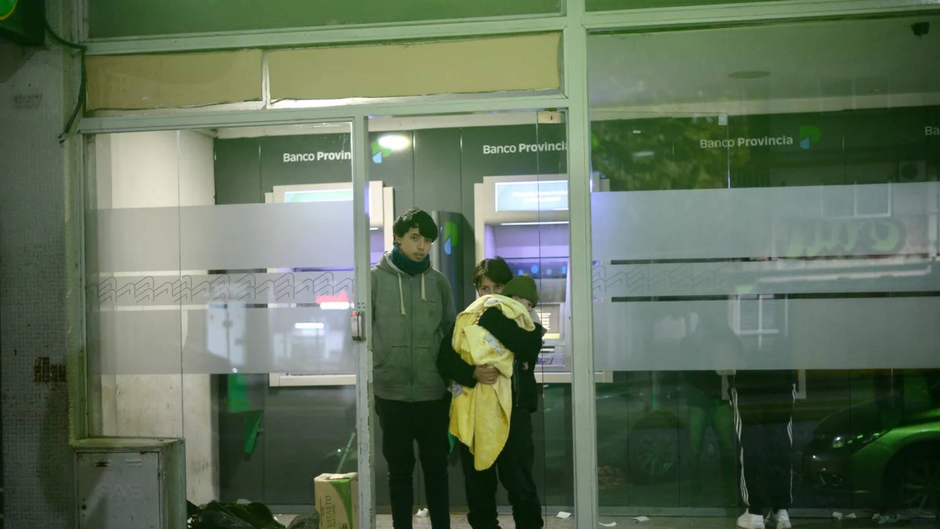 Hugo, Sofía y Lucas, de un año, en la puerta del cajero donde solían pasar la noche.