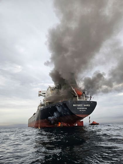Humo emerge del Mayuree Naree, un buque granelero con bandera de Tailandia, tras ser impactado por un proyectil en el estrecho de Ormuz, al norte de Omán