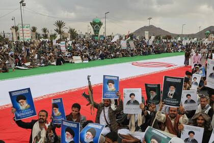 Hutíes sostienen carteles del líder supremo de Irán, el ayatolá Ali Khamenei, que murió en un ataque de Israel y EEUU, junto a una enorme bandera iraní mientras protestan contra la guerra contra Irán, en Saná, Yemen, viernes 6 de marzo de 2026. (Foto AP/Osamah Abdulrahman)