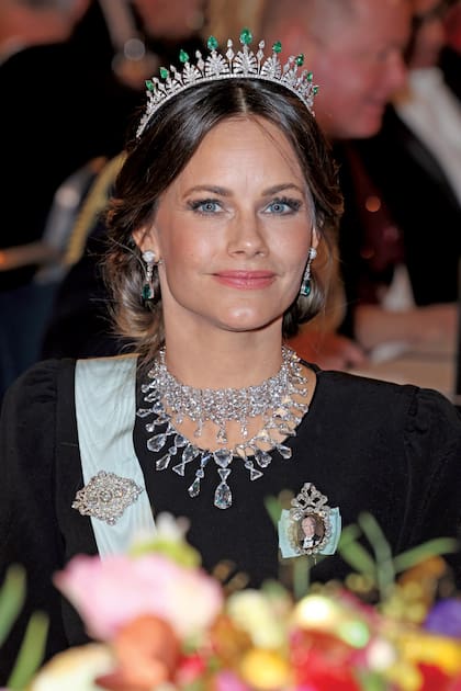 Ícono de estilo, la princesa Sofía optó por un vestido de cuello redondo, con hombreras y cintura marcada, de Andiata. Además de la tiara con esmeraldas, llevó choker, collar y brazalete realizados con rodio, plata y cristales, todo de Swarovski. El clutch era de Bottega Veneta.