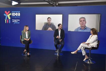 Agustina Fainguersch (Wolox), Lalo Zanoni (moderador) y Azucena Gorbarán (AMG Consulting Group). En las pantallas: Ignacio Imaz (Crucijuegos) y Sebastián Miranda (Farmacity)