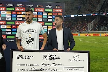 Ignacio Vazquez, defensor de Platense, recibió un premio de 10.000.000 de pesos como mejor jugador del semestre en Argentina; se lo entregó Ariel Vallejo, de Sur Finanzas.