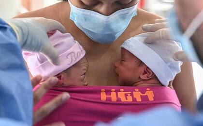 Imagen de archivo del 21 de mayo de 2020 donde una madre amamanta a sus gemelos recién nacidos mientras un médico la ayuda, durante la pandemia del coronavirus , en la sala de lactancia postnatal del Hospital General de Medellín, en Medellín. (Foto: Joaquín Sarmiento - AFP)