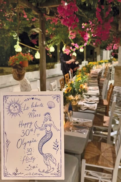 Imagen de la tarjeta de invitación; detrás, la larga mesa de la
Taverna Klimatari decorada con girasoles