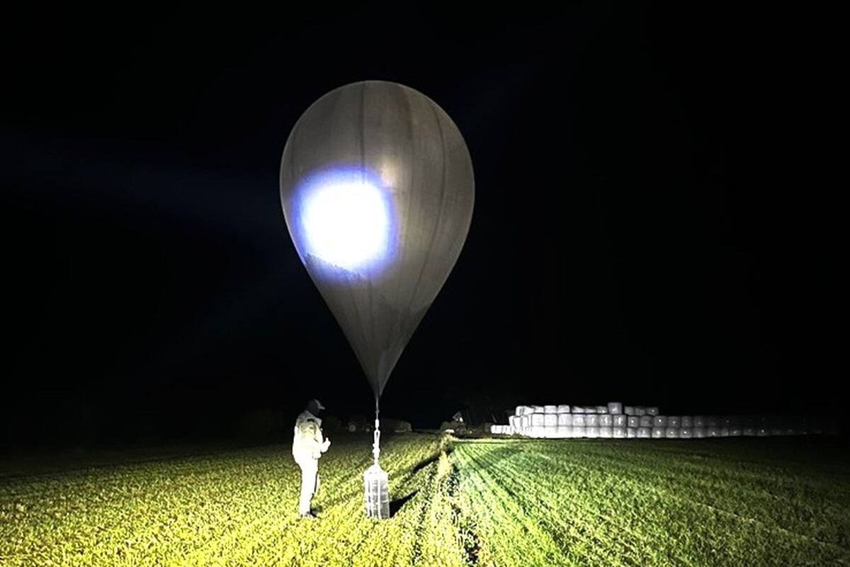Imagen sin fecha proporcionada por la Guardia Estatal de Fronteras un agente inspecciona un globo utilizado para llevar cigarrillos a Lituania