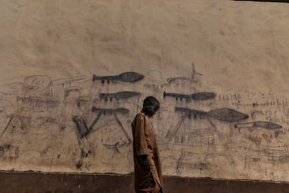 "La crisis del lago Chad", fue galardonado con el primer premio en la categoría Medio ambiente, Historias, muestra a un niño huérfano que pasa junto a una pared con dibujos de lanzagranadas en Bol, Chad