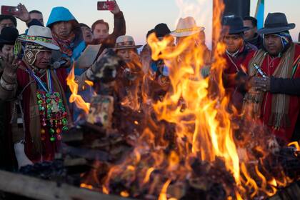 Indígenas aymaras queman ofrendas en honor a la Pachamama o Madre Tierra, después de recibir los primeros rayos de sol en un ritual de Año Nuevo en la montaña Murmutani en las afueras de Hampaturi, Bolivia, la madrugada del miércoles 21 de junio de 2023. (AP Foto/Juan Karita)