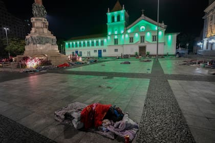 Indigentes duermen en la plaza Patio do Colegio en el centro de Sao Paulo, Brasil, viernes 20 de mayo de 2022. La municipalidad habilitó estaciones del metro para los indigentes debido a una ola de frío intenso. (AP Foto/Andre Penner)