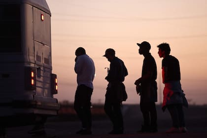 Inmigrantes que buscan asilo esperan para abordar un autobús a un centro de procesamiento de la Patrulla Fronteriza de EE. UU., después de cruzar a Arizona desde México, el 11 de mayo de 2023 en Yuma, Arizona