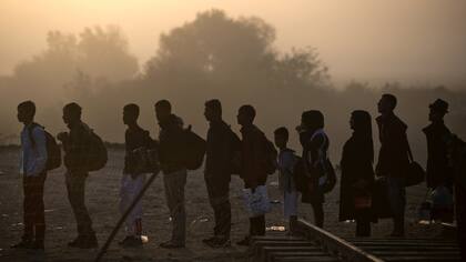 Inmigrantes y refugiados hacen cola para cruzar de Grecia a Macedonia, cerca de Gevgelija
