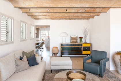 Insertado en las vigas, un riel con luces orientables 'Track' (Flos), sillón 'Utrecht' (Cassina) y lámpara 'Atollo' (Oluce). El vano deja ver el comedor, la cocina y la terraza posterior.