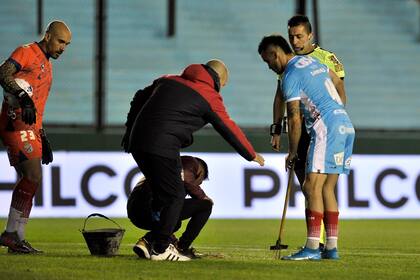 Insólito: Christian Chimino, con un palo con puntas, ayuda a los auxiliares a cubrir el pozo que demoró por unos minutos Arsenal vs. Talleres en la Liga Profesional de Fútbol.