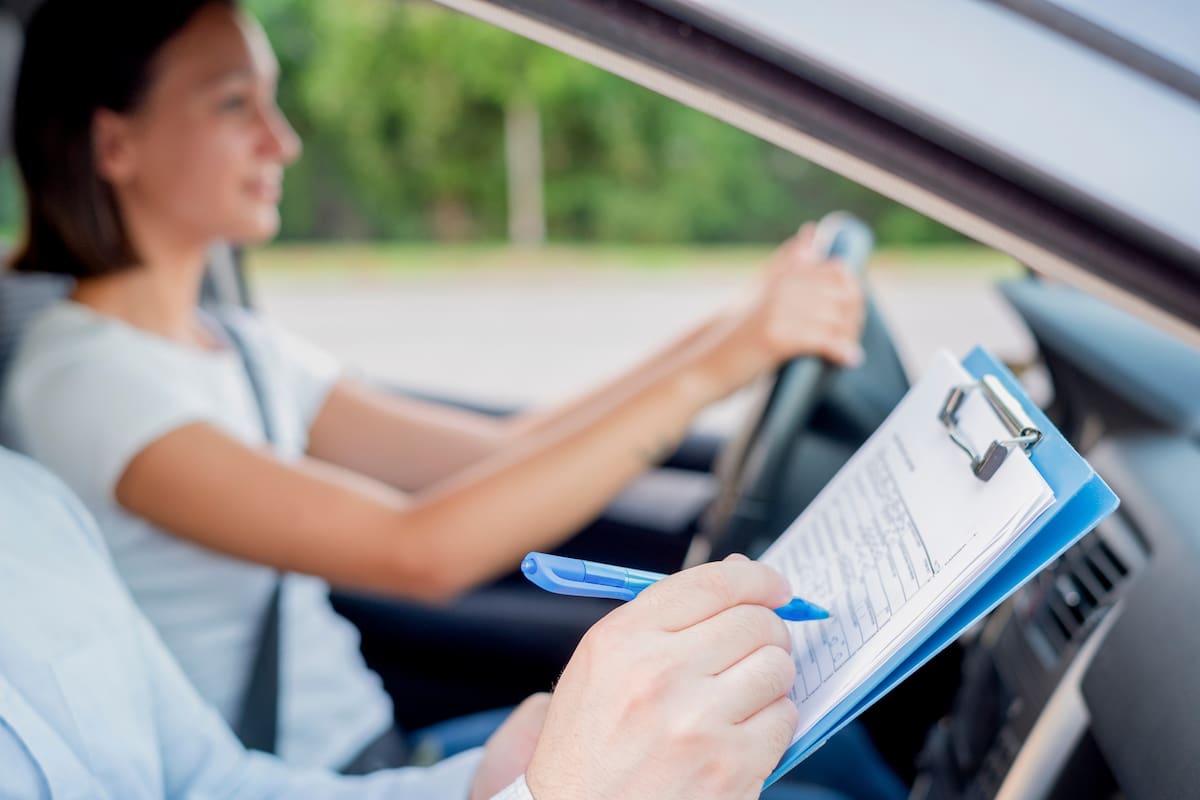 Instructor of driving school giving exam while sitting in car