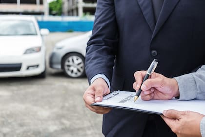 Insurance Agent examine Damaged Car and customer filing signature on Report Claim Form process after accident, Traffic Accident and insurance concept.