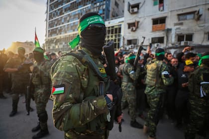 Integrantes de las Brigadas Qassam, el ala militar de Hamas, controlan a una multitud ante la llegada de los vehículos de la Cruz Roja para recoger a rehenes israelíes el 19 de enero de 2025
