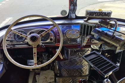 Interior de un colectivo de los 70, el asiento del chofer, el volante y sus boleteras con rollos de boletos, sus monederos y el fileteado porteño que los decora