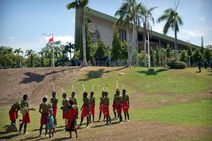 Intérpretes con trajes tradicionales se ven de pie ante el parlamento en Port Moresby, Papúa Nueva Guinea.