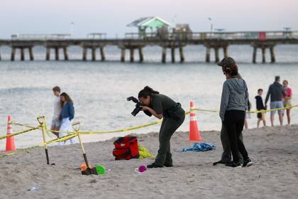 Investigadores en la playa de Lauderdale-by-the-Sea, Florida, toman fotografías de la escena de un colapso de arena el martes 20 de febrero de 2024