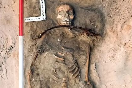 Investigadores en Polonia excavaron a una mujer del siglo XVII enterrada con una hoz alrededor del cuello y un candado en el pie. Cerca estaban los restos de un niño con un candado bajo el pie (Łukasz Czyżewski)