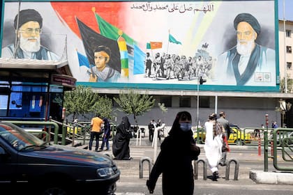Iraníes caminan junto a un cartel del ayatollah Alí Khamenei (izquierda) y el líder de la Revolución Islámica, Ruhollah Khomeini (derecha) (Foto de ATTA KENARE / AFP)
