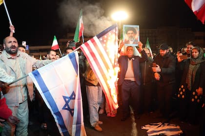 Iraníes queman banderas de Estados Unidos e Israel mientras reaccionan tras el anuncio del alto el fuego en la plaza Enqelab, en Teherán, el 8 de abril de 2026