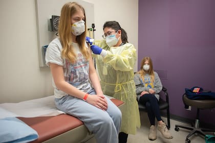 Isabelle King, de 14 años, recibe su segunda dosis de la vacuna Moderna de Jallesse Flores, mientras su hermana gemela, Alexandra, observa, en Houston, el 5 de febrero de 2021