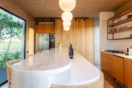 Isla de kiri con mesada a 1,10 m. de altura con tapa de mármol ‘Blanco Turco’; la más baja, de Corian, al igual que la mesada principal con mueble de kiri (Leone Loray)